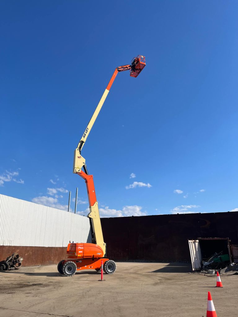 A fully extended boom lift reaching high into the sky with a worker in the platform A fully extended boom lift reaching high into the sky with a worker in the platform