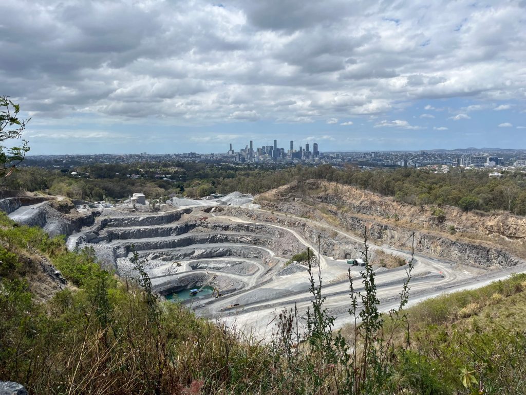 A view of a quarry site with a distant skyline in the background, showing urban development near an extraction site A view of a quarry site with a distant skyline in the background, showing urban development near an extraction site