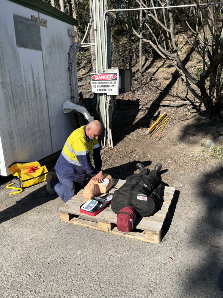 A worker in high-vis clothing performing CPR on a mannequin during a first aid training session, reinforcing safety and emergency preparedness A worker in high-vis clothing performing CPR on a mannequin during a first aid training session, reinforcing safety and emergency preparedness